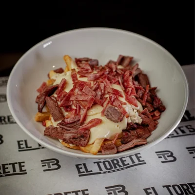 Papas locas Torete Beef con carne, pollo, queso fundido y tocineta ahumada servidas con salsas en El Torete Burger.